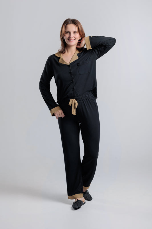 Woman wearing a classic  black bamboo loungewear set with champaign accents and trims . button down black soft pyjama for women